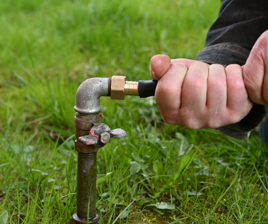 A person fixing a leaky outdoor faucet