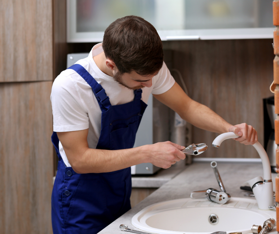 A person unscrewing a faucet base of a Moen kitchen faucet
